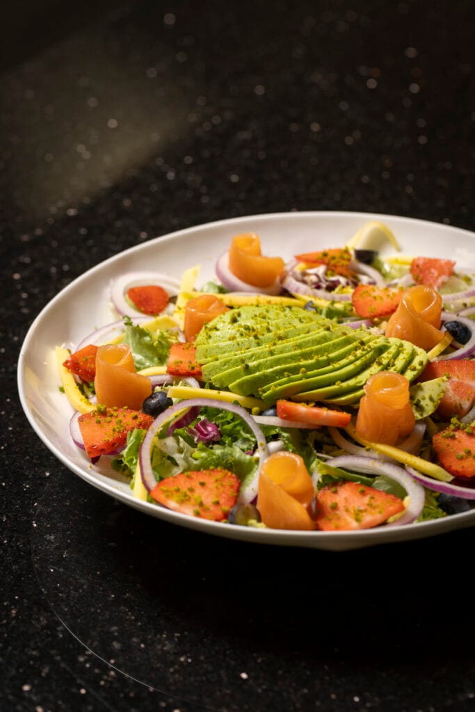 Ensalada fresca de salmón, aguacate y fresas. Descubre el producto de temporada en El Racó de la Xara, tu restaurante íntimo de la Marina Alta.